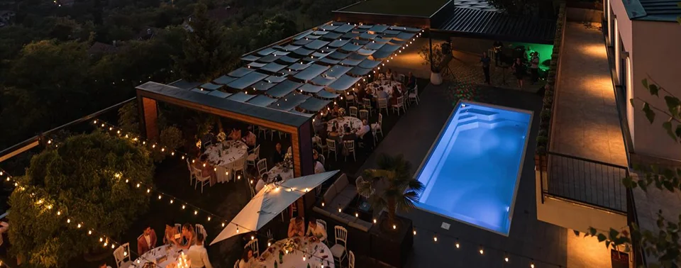 Rooftop de BoH de noche con piscina iluminada y luces colgantes